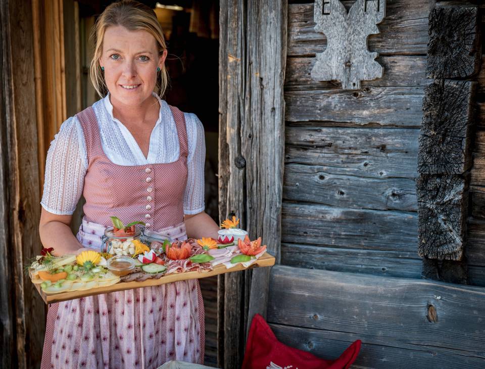 Gastwirtin serviert ein Frühstücksbrett auf der Au Hochalm